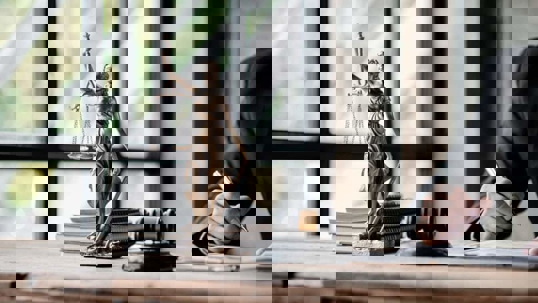 Close-up of a desk with law symbols, like the Scales of Justice and a gavel.