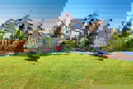 A well-kept gray house with brick and landscaping fills the frame.